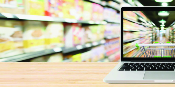 Laptop sitting on wooden bench with image of shopping trolley and blurred supermarket aisle shelves.